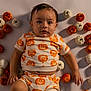 baby, child, pumpkin, orange, white, patterned_clothing, bracelet, lying_down, cute, holiday, halloween, autumn, decor, small_pumpkins, infant, portrait, indoors, skin, face, hand