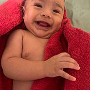 Alessandro is registered to the contest to win money with this photo: baby, infant, smiling, red_towel, naked, skin, hand, face, expression, happy, cute, indoors, blanket, young_child, child, portrait, human, lying_down, warm, comfort