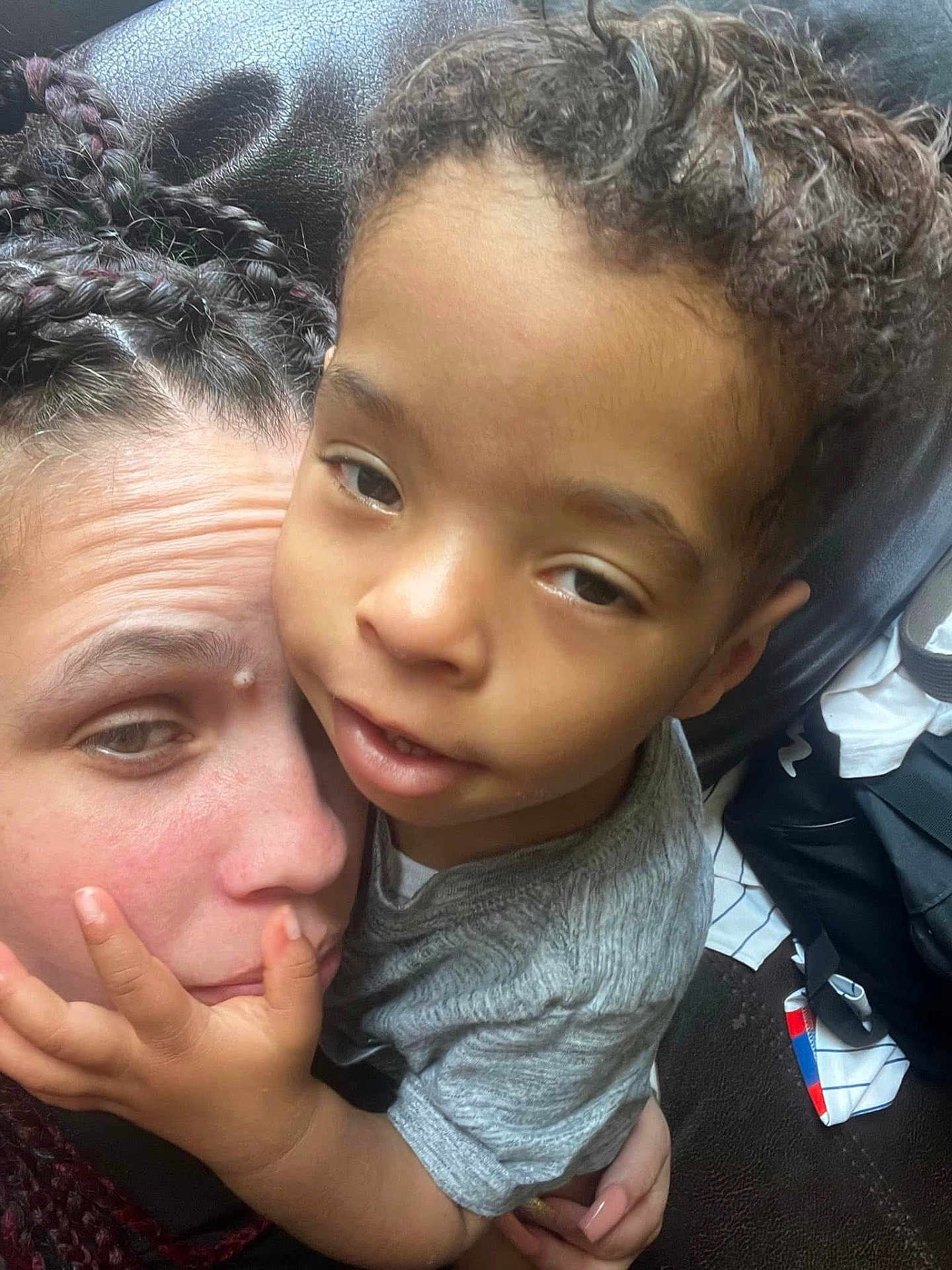 Abel joined the competition — help win amazing prizes! child, adult, face, hand, hair, curly_hair, braided_hair, skin, hugging, affection, close_up, indoor, casual_clothing, leather, black_leather, expression, portrait, intimacy, family, love