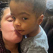 Abel is registered to the contest to win money with this photo: child, adult, kiss, affection, close_up, couch, indoor, love, family, braids, gray_shirt, skin, hand, portrait, comfort, casual_clothing, expression, toddler, holding, leather