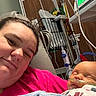 Mac is registered to the contest to win money with this photo: adult, baby, blanket, hospital, medical_equipment, nasal_cannula, person, portrait, resting, smiling, sleeping, indoor, care, healthcare, mother_and_child, closeup, comfort, hospital_room, patient, family