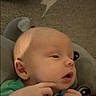 Mac is registered to the contest to win money with this photo: baby, infant, face, hand, pacifier, plush_toy, blanket, green_clothing, skin, ear, head, expression, closeup, child, person, young, indoors, soft_toy, couch, comfort