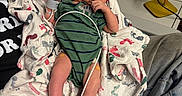 Mac is registered to the contest to win money with this photo: baby, newborn, infant, hospital, blanket, footprints, wristband, clothing, person, lying, medical, monitoring, wire, hand, foot, green_onesie, curious, indoors, bed, care