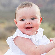 Charlotte is registered to the contest to win money with this photo: baby, child, smile, face, white_dress, happy, outdoor, portrait, cute, infant, skin, cheeks, eyes, person, nature, daylight, young, baby_girl, closeup, human