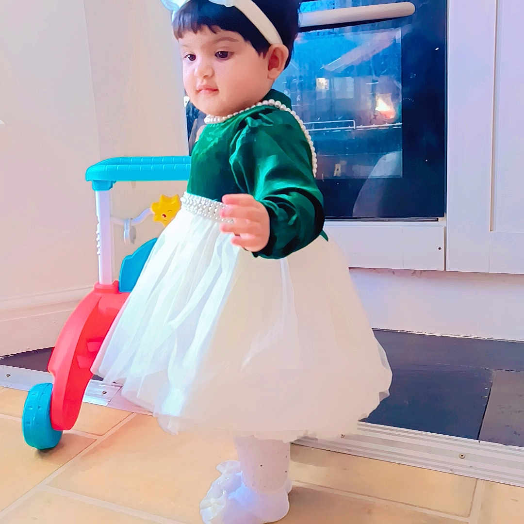 Nabiha is registered to the contest to win money with this photo: baby, bodypart, cap, clothing, costume, dress, face, finger, footwear, formalwear, hand, hat, head, indoors, interiordesign, person, photography, portrait, sitting, skirt