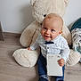 baby, child, teddy_bear, plush_toy, floor, indoor, jeans, shirt, bow_tie, notepad, smiling, blue_eyes, shoes, wooden_floor, cute, toy, seated, happy, person, home