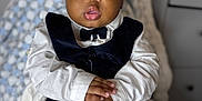 Joel joined the competition — help win amazing prizes! baby, child, infant, portrait, face, hands, clothing, vest, bow_tie, plaque, milestone, four_months, blanket, indoor, person, cute, skin, eyes, expression, holding