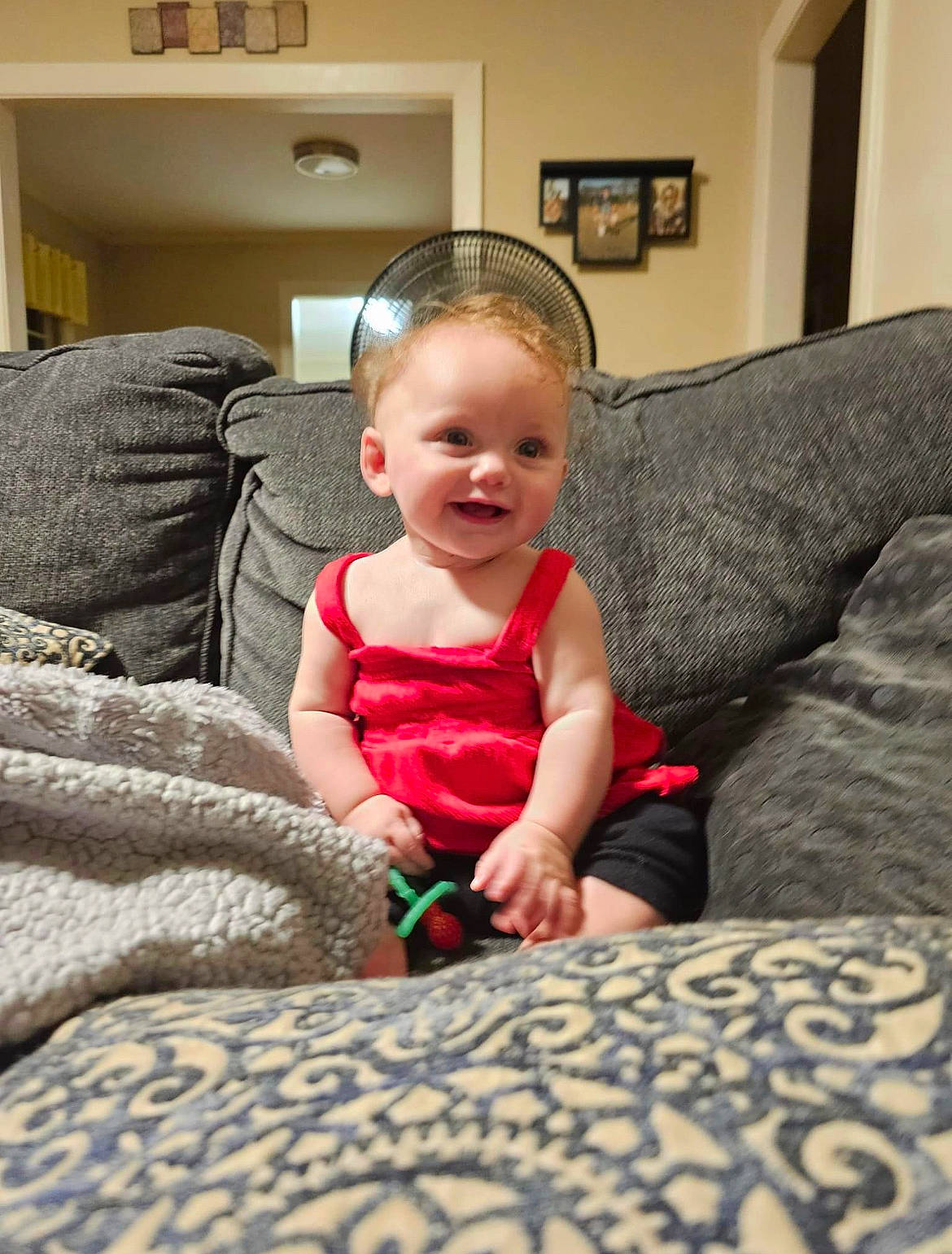 Adalyne joined the competition — help win amazing prizes! baby, baby_toddler_clothing, child, comfort, couch, flooring, fun, happy, linens, living_room, pattern, person, picture_frame, room, shelf, sitting, smile, t_shirt, thumb, toddler