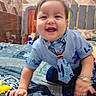 baby, bedspread, blue_shirt, bracelet, child, crawling, cute, face, happy, home, indoor, infant, patterned, person, playful, smiling, tie, tiles, toy, young_child