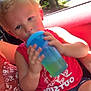 child, blonde_hair, blue_cup, red_shirt, shorts, stars_pattern, car_interior, seat, sunlight, forest, window, person, hand, sitting, drink, summer, casual_clothing, young, portrait, relaxed