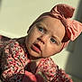 Lainey is registered to the contest to win money with this photo: baby, child, blue_eyes, pink_bow, headband, floral_outfit, carpet, indoors, portrait, closeup, cute, infant, expression, sunlight, soft_light, hand, face, person, clothing, curious