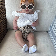 Lainey joined the competition — help win amazing prizes! baby, sunglasses, headband, bow, white_top, leopard_print, couch, beige, sitting, infant, cute, fashion, child, portrait, sock, furniture, indoor, closeup, person, adorable