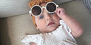 Lainey joined the competition — help win amazing prizes! baby, child, sunglasses, headband, white_top, leopard_print, couch, beige, blue_eyes, infant, fashion, cute, portrait, indoor, person, clothing, hand, face, relaxed, accessory