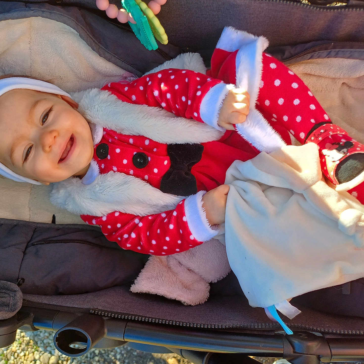 Sarah participe au concours pour gagner de l'argent avec cette photo : baby, blanket, child, cozy, cute, face, footwear, fur_trim, hand, happy, headwear, infant, outdoor, polka_dot, red_clothing, smile, stroller, sunlight, toy, warm_clothing