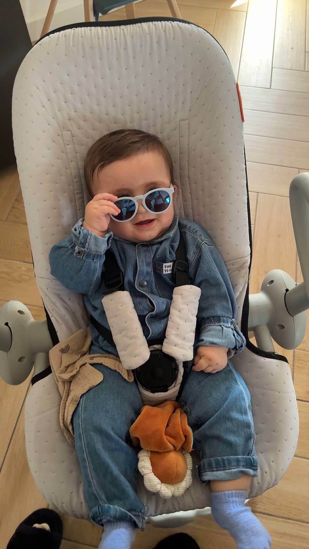 accessories, baby, clothing, coat, cushion, face, footwear, furniture, glasses, head, homedecor, jacket, jeans, pants, person, photography, portrait, shoe, sitting, sunglasses