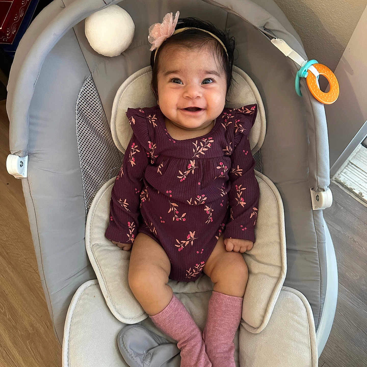 Harnoor joined the competition — help win amazing prizes! baby, baby_seat, bouncer, chubby_cheeks, cozy, cute, dark_hair, hands, happy, headband, indoor, infant, legs, onesie, pink_socks, portrait, smiling_baby, soft_ball, toy_ring, wood_floor