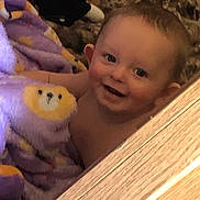 Chance joined the competition — help win amazing prizes! baby, child, blanket, purple_blanket, lion_face, smiling, happy, face, skin, head, person, indoor, wood, texture, cozy, cute, infant, young_child, wrapped, peek