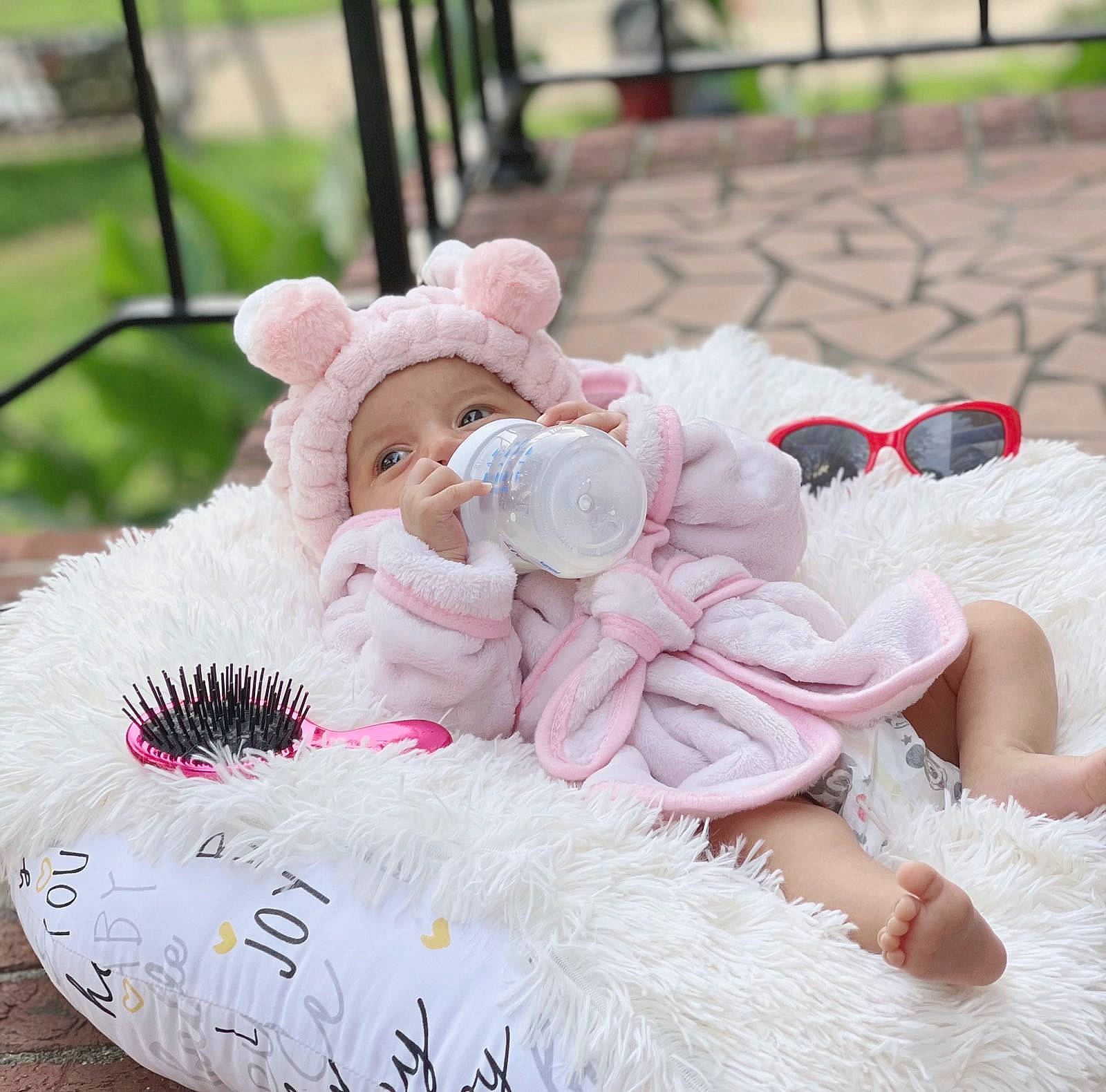 Miral joined the competition — help win amazing prizes! baby_toddler_clothing, carmine, child, comfort, fur, goggles, grass, happy, headwear, linens, magenta, pattern, peach, person, petal, pink, plush, sitting, stuffed_toy, sweetness