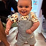 Kaïs participe au concours pour gagner de l'argent avec cette photo : adult, baby, background, cartoon_shirt, child, clothing, cute, denim_overalls, expression, face, floor, footwear, furniture, happy, indoor, person, sandals, skin, smile, standing
