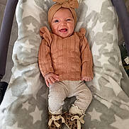 Ava participe au concours pour gagner de l'argent avec cette photo : baby, infant, smiling, headwrap, brown_sweater, leopard_print_shoes, blanket, star_pattern, cozy, cute, happy, indoors, portrait, child, clothing, footwear, warm, soft, lying_down, newborn