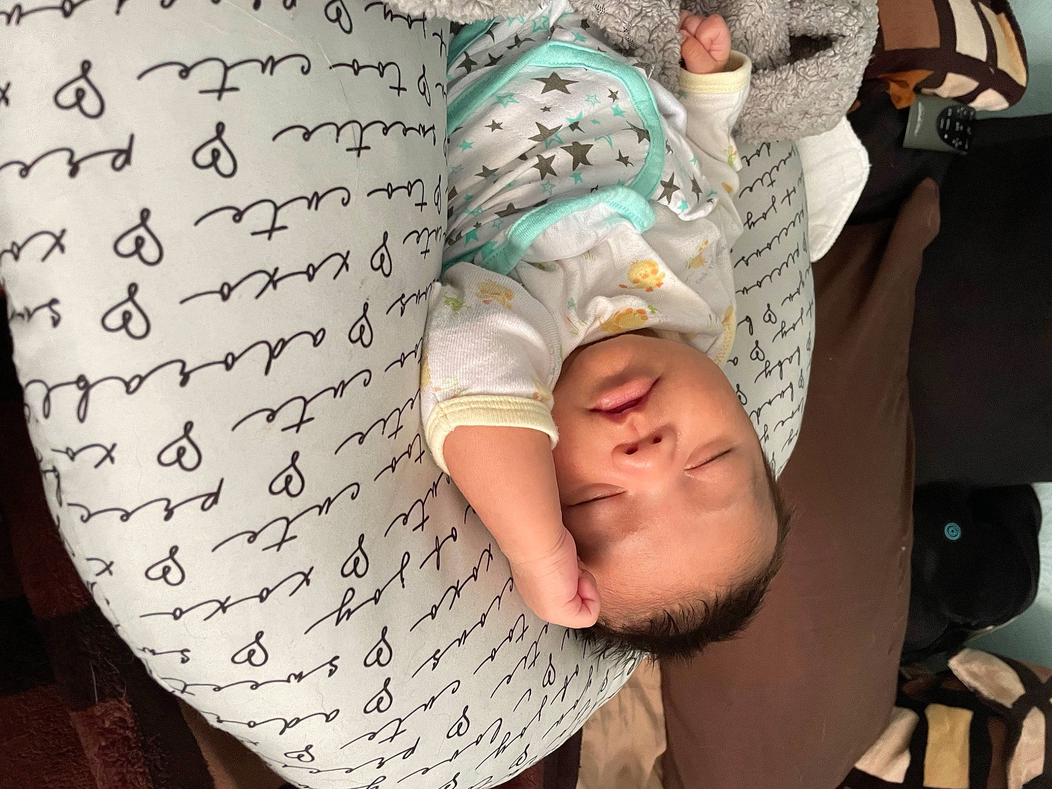 Georgie is registered to the contest to win money with this photo: baby, cap, child, comfort, elbow, facial_expression, finger, flooring, font, happy, human_leg, linens, pattern, person, room, sitting, t_shirt, textile, thigh, toddler