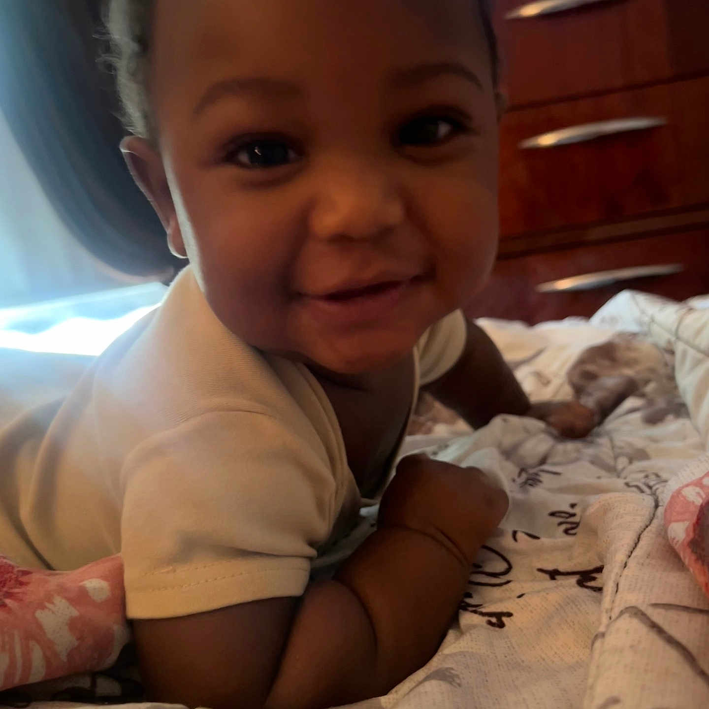 Zahir is registered to the contest to win money with this photo: baby, infant, smiling, face, bed, blanket, furniture, indoor, child, person, cute, happy, skin, arm, wood, drawer, cozy, portrait, baby_clothes, lying_down