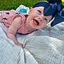 baby, child, smiling, headband, bow, outdoor, grass, blanket, happy, face, blue_eyes, cute, infant, summer, sunlight, patterned_clothing, red_stripes, white_blanket, lying_down, portrait