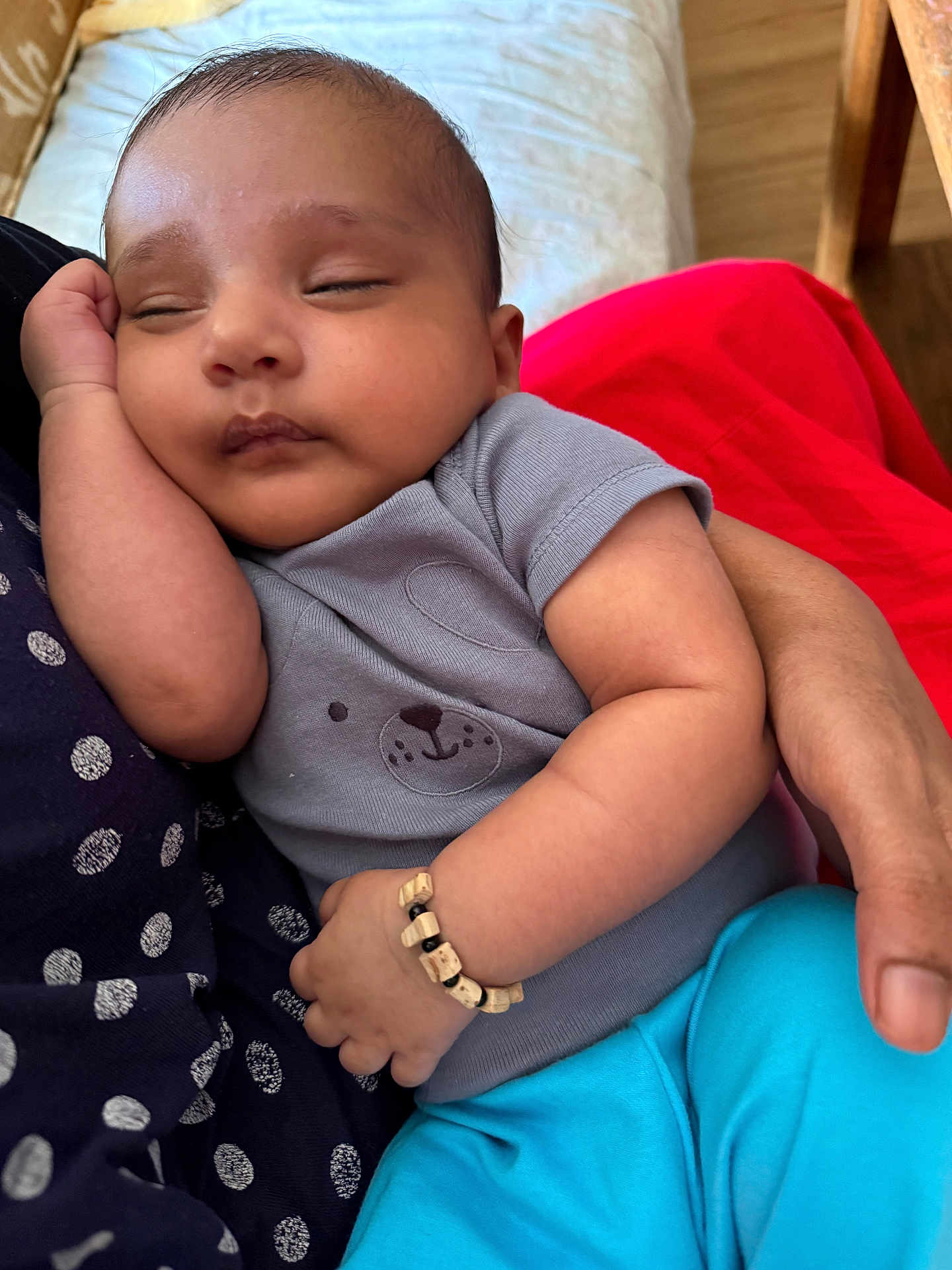 Waqqas is registered to the contest to win money with this photo: baby, sleeping, arm, bracelet, clothing, person, hand, face, polka_dot, shirt, blue_pants, wood_floor, couch, fabric, rest, closeup, cute, infant, relaxation, casual