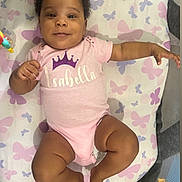 Brielle is registered to the contest to win money with this photo: baby, infant, onesie, pink_clothing, smile, face, child, butterfly_pattern, blanket, laying_down, happy, cute, skin, person, indoors, toy, hand, feet, curly_hair, playpen