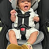 Nolan joined the competition — help win amazing prizes! baby, child, car_seat, safety_harness, hat, white_clothing, smile, happy, infant, footwear, yellow_shoes, seat_padding, indoor, person, cute, small_hands, small_feet, headwear, secured, portrait