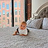 Nolan is registered to the contest to win money with this photo: baby, infant, bed, quilt, pillow, window, blinds, brick_building, indoor, curious, crawling, white_bib, head, face, person, child, room, daylight, home, cozy