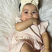 Eilany is registered to the contest to win money with this photo: baby, girl, infant, headband, bow, pink_dress, fluffy_rug, hand_in_mouth, cute, smiling, portrait, child, soft_texture, indoor, close_up, skin, face, eyes, young, comfortable