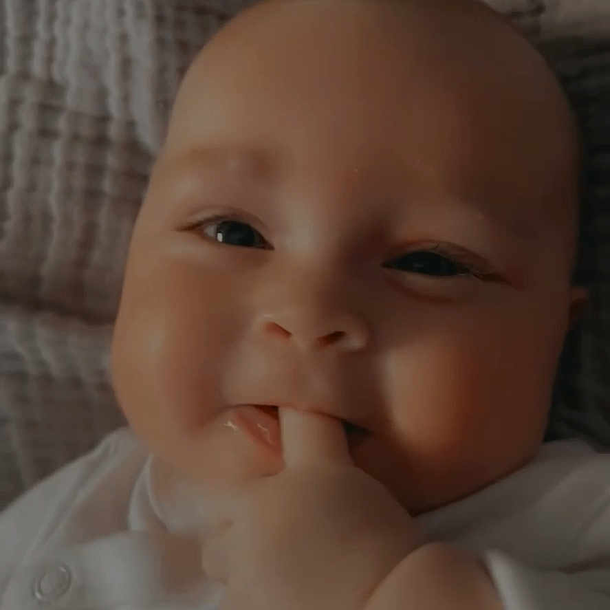 Rylee is registered to the contest to win money with this photo: baby, blanket, cheeks, closeup, cute, expression, eyes, face, fingers, hand, head, indoors, infant, mouth, portrait, skin, smile, soft_texture, white_clothing, young_child