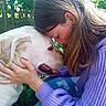 Jouck a rejoint le concours — aidez-le/la à gagner de superbes lots ! woman, person, dog, pet, animal, canine, white_dog, portrait, cuddle, affection, nuzzling, smiling, outdoor, garden, greenery, leaves, sunlight, purple_sweater, long_hair, hand
