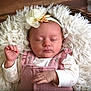 baby, infant, sleeping, headband, flower, pink_clothing, white_clothing, basket, fluffy_cushion, soft_texture, peaceful, newborn, closeup, portrait, indoors, cute, hand, face, resting, cozy