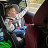 toddler, child, car_seat, safety_harness, car_interior, window, smiling, happy, jeans, hoodie, seat, automobile, travel, seatbelt, young_child, person, casual_clothing, daytime, nature_outside, road