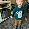 Leelend is registered to the contest to win money with this photo: toddler, child, smiling, blue_eyes, sweater, clothing, living_room, carpet, toys, christmas_tree, holiday_decor, furniture, television, binoculars, person, happy, indoors, books, storage_bin, home