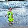 toddler, child, water, beach, ocean, splashing, neon_clothing, yellow_shorts, yellow_shirt, happy, smiling, sand, waves, sky, clouds, outdoor, summer, vacation, nature, play