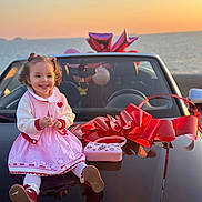 Ayline participe au concours pour gagner de l'argent avec cette photo : child, toddler, car, red_bow, sunset, ocean, pink_dress, smiling, curly_hair, outdoor, happy, toy_purse, balloons, reflection, vehicle, holiday, celebration, cute, fashion, portrait