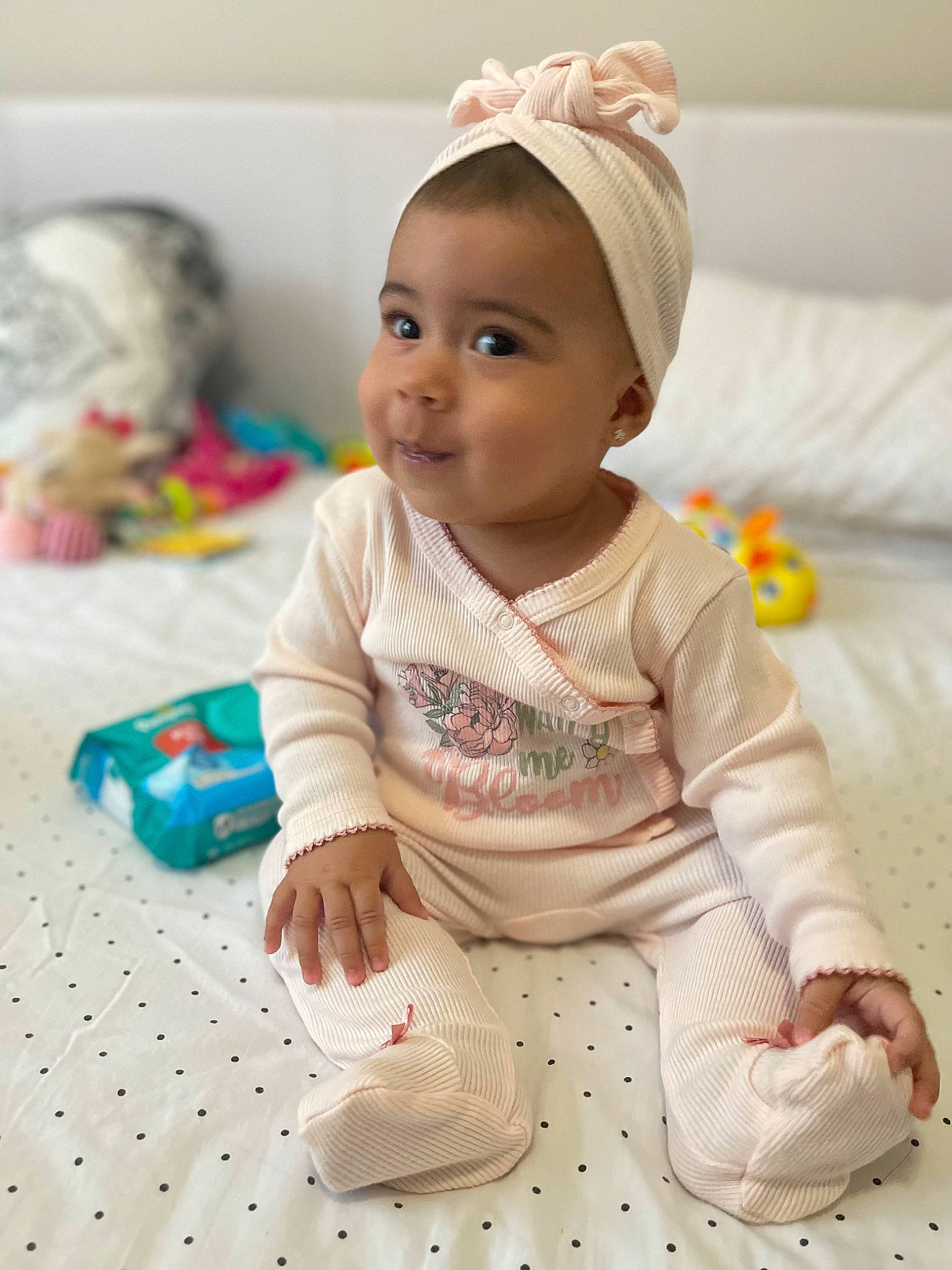 Amy is registered to the contest to win money with this photo: baby, baby_toddler_clothing, cheek, child, dress, eye, face, flooring, happy, pattern, person, pink, product, room, sitting, skin, sleeve, smile, textile, toddler