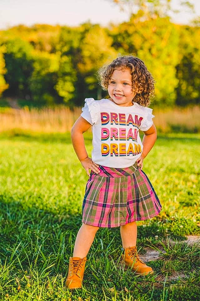 Sarai is registered to the contest to win money with this photo: baby_toddler_clothing, child, dress, flash_photography, fun, grass, grassland, happy, joy, meadow, people_in_nature, person, plaid, plant, recreation, smile, sunlight, tartan, toddler, tree