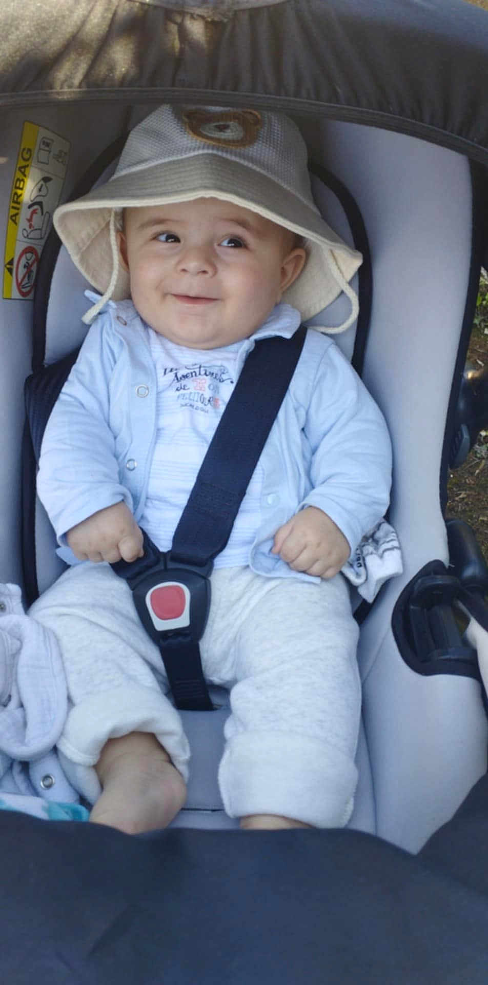 Nadir participe au concours pour gagner de l'argent avec cette photo : baby, bucket_hat, car_seat, child, smile, cute, straps, clothing, infant, sitting, outdoor, happy, face, headwear, safety, car, baby_clothes, footwear, blanket, seatbelt