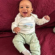 Aziel is registered to the contest to win money with this photo: baby, smiling, child, sitting, white_shirt, mint_green_pants, bunny_print, carrot_print, couch, maroon, textured, happy, infant, cute, portrait, indoors, sock, clothing, person, young_child