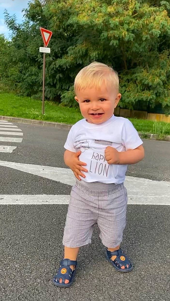 Eliano participe au concours pour gagner de l'argent avec cette photo : asphalt, baby_toddler_clothing, child, electric_blue, flag, fun, grass, happy, joy, leisure, person, plant, public_space, recreation, road_surface, sandal, shorts, sleeve, smile, t_shirt