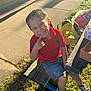 Mateo joined the competition — help win amazing prizes! child, smile, outdoor, bench, sunlight, shadow, grass, pavement, braided_hair, red_shirt, denim_shorts, sneakers, backpack, carton, happy, person, casual_clothing, playground, daylight, portrait