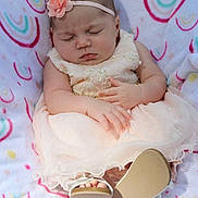 Kaliyah is registered to the contest to win money with this photo: baby, sleeping, dress, headband, flower, blanket, pattern, footwear, sandals, infant, cute, peaceful, soft, pink, hands, feet, child, portrait, indoors, resting