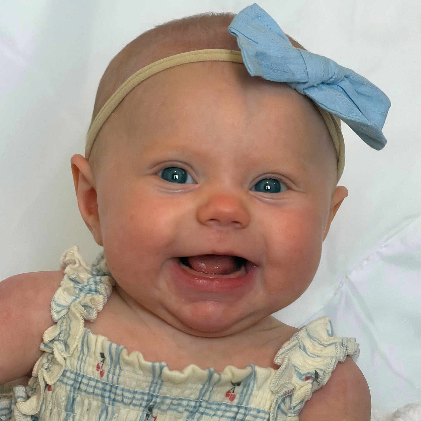 Haisley is registered to the contest to win money with this photo: baby, smiling, blue_eyes, headband, bow, dress, ruffles, infant, cute, happy, portrait, child, skin, face, person, indoors, closeup, young, sitting, white_background