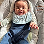 baby, baby_seat, bib, child, clothing, comfortable, cozy, cushion, cute, face, happy, indoors, infant, natural_light, person, portrait, relaxed, smiling, striped_sleeves, young