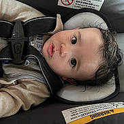 Xavian joined the competition — help win amazing prizes! baby, car_seat, harness, child, infant, face, curly_hair, eyes, clothing, warning_label, seat, straps, head_support, indoor, closeup, expression, cute, young, sitting, person