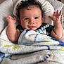 baby, black_shirt, blanket, child, cozy, curly_hair, cute, expression, face, furniture, happy, indoors, infant, pacifier_clip, portrait, raised_hands, skin, smiling, soft_toy, toddler